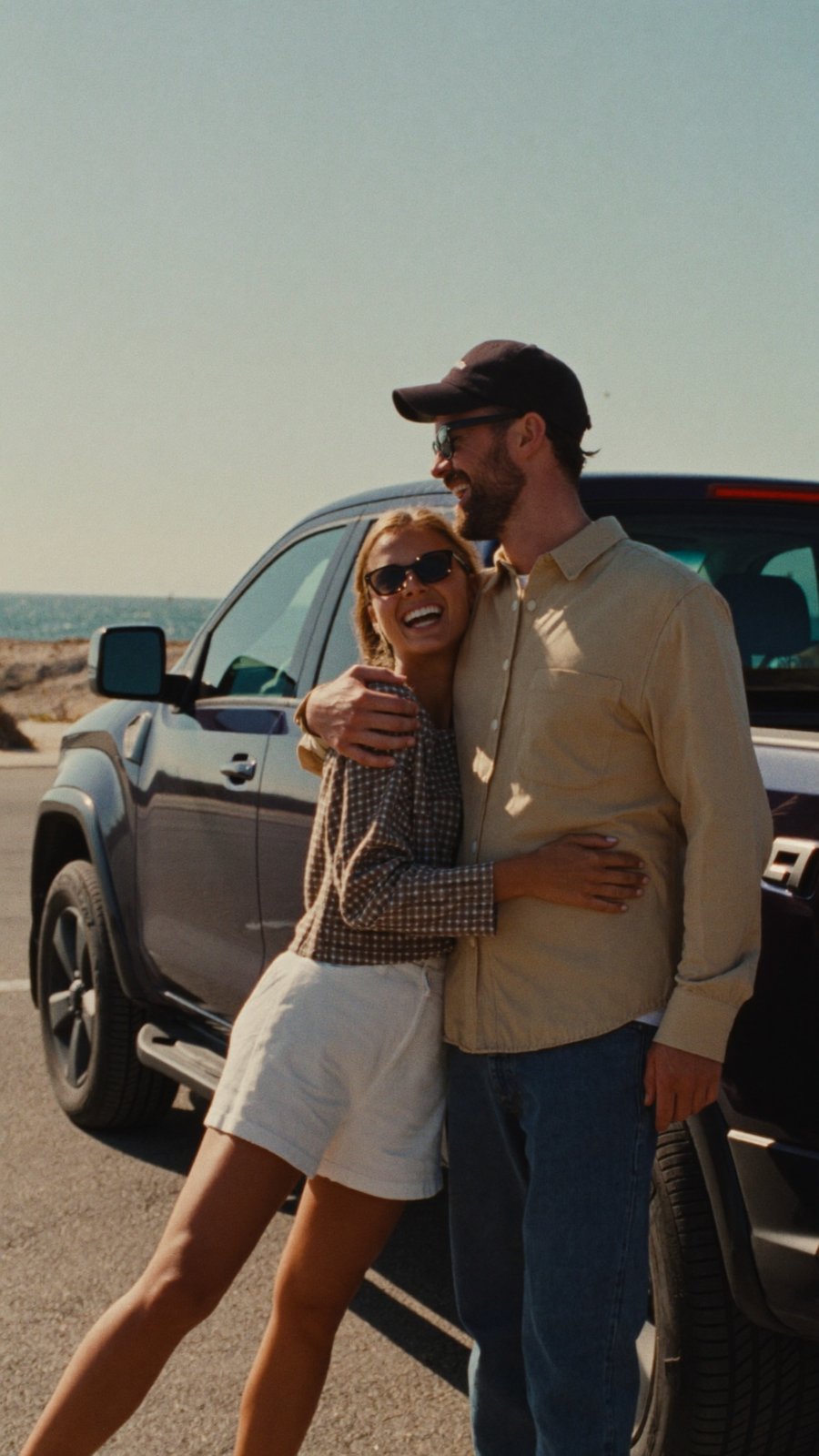 A couple standing with their new pickup near the shore